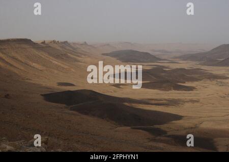 Makhtesh Ramon, un énorme cratère créé par l'érosion dans l'ancienne époque géologique, les collines noires sont des dépôts basalte roches, désert de Negev, Israël. Banque D'Images