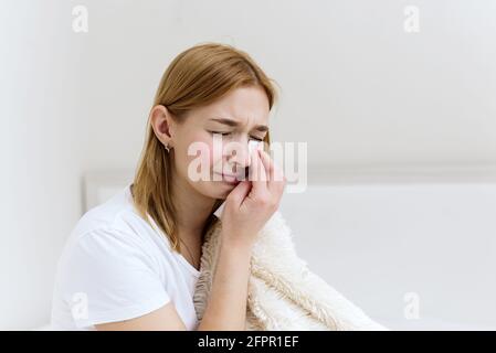 Cœur brisé, concept de maison. La triste femme essuie les larmes de son visage et les pleurs. Fille solitaire assise sur un lit d'appartements. Banque D'Images