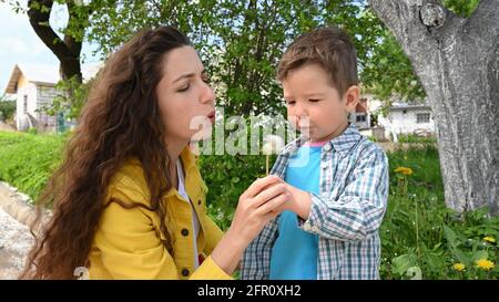 Maman et enfant soufflent un pissenlit. Banque D'Images