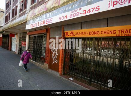 Vancouver, Canada. 20 mai 2021. Une femme passe devant des magasins fermés le long d'une rue à Chinatown, Vancouver, Colombie-Britannique, Canada, le 20 mai, 2021. Après avoir souffert de la pandémie COVID-19 pendant plus d'un an, les entreprises de Chinatown, l'une des attractions touristiques de Vancouver, demandent de l'aide pour ramener les visiteurs. Credit: Liang Sen/Xinhua/Alay Live News Banque D'Images