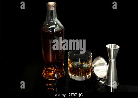 Vieux verre à fashon à côté de la bouteille avec des pierres à whisky Scotch entonnoir de mesure pour servir le liquide doré Banque D'Images