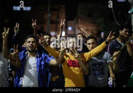 Les Palestiniens chantent des slogans tout en célébrant dans la rue après le cessez-le-feu dans le nord de la bande de Gaza. Israël et les deux principaux groupes armés palestiniens de Gaza, le Hamas et le Jihad islamique, ont annoncé un cessez-le-feu le 21 mai 2021, dans le but de mettre fin au conflit le plus dévastateur entre eux pour une période de sept ans. La trêve négociée par l'Égypte a été annoncée après la pression internationale croissante visant à mettre fin aux 11 jours de conflit qui ont coûté la vie aux deux parties, alors que des avions de guerre israéliens bombardent Gaza par des frappes aériennes, tandis que des militants ont tiré des milliers de roquettes vers Israël. Banque D'Images