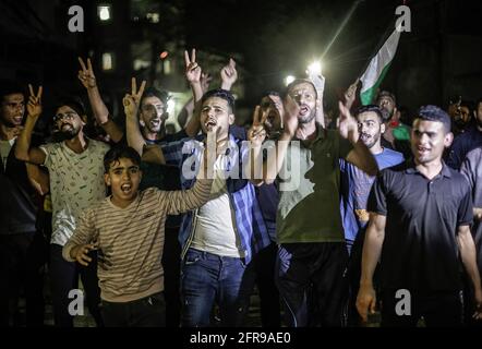 Les Palestiniens chantent des slogans tout en célébrant dans la rue après le cessez-le-feu dans le nord de la bande de Gaza. Israël et les deux principaux groupes armés palestiniens de Gaza, le Hamas et le Jihad islamique, ont annoncé un cessez-le-feu le 21 mai 2021, dans le but de mettre fin au conflit le plus dévastateur entre eux pour une période de sept ans. La trêve négociée par l'Égypte a été annoncée après la pression internationale croissante visant à mettre fin aux 11 jours de conflit qui ont coûté la vie aux deux parties, alors que des avions de guerre israéliens bombardent Gaza par des frappes aériennes, tandis que des militants ont tiré des milliers de roquettes vers Israël. Banque D'Images