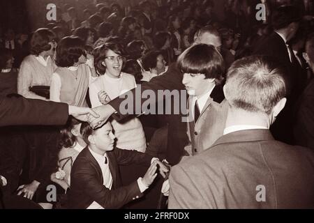 La police se joint à la main pour retenir les fans adoring tandis que Ringo Starr se promène au Washington Coliseum de Washington, D.C. où les Beatles jouaient dans leur premier concert américain le 11 février 1964. (ÉTATS-UNIS) Banque D'Images