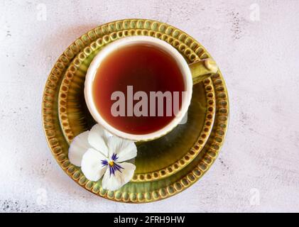 Une tasse de thé en céramique verte et deux soucoupes décorées de fleurs sur un fond clair. Vue de dessus. Concentrez-vous sur la fleur. Banque D'Images