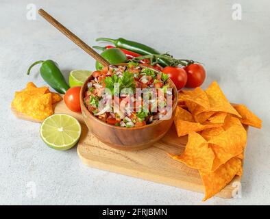 Apéritif mexicain Pico de Gallo dans un bol et ingrédients sur la table. Banque D'Images