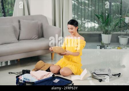 une femme heureuse emballe une valise à la maison Banque D'Images