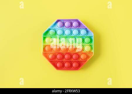 Nouveau silicone populaire tendance coloré anti stress Pop IT jouet pour enfant sur fond jaune. Vue de dessus. Pousser la bulle pop. Banque D'Images
