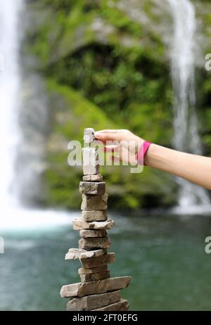 main de la petite fille qui construit une pile de pierres pour identifier l'orientation dans les montagnes appelées par Alpinistes CAIRN ou petit homme Banque D'Images