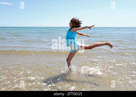 une jeune fille athlétique effectue un grand saut sur la mer Pendant des exercices de gymnastique rythmique pour garder la forme pendant l'été Banque D'Images