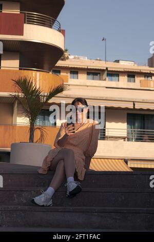 fille avec robe jaune et des lunettes envoyant un son avec le mobile Banque D'Images