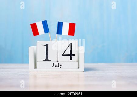 Calendrier en bois du 14 juillet avec drapeaux de France miniatures. Concepts de la fête nationale française, de la fête de la Bastille et de la fête heureuse Banque D'Images