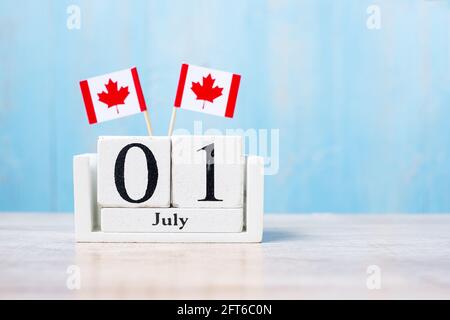 Calendrier en bois du 1er juillet avec drapeaux miniatures du Canada. Concepts de la fête du Canada et de la célébration heureuse Banque D'Images