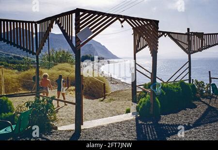 Image d'archivage. La plage d'Agia Galini en Crète avec les montagnes lointaines, à la sortie d'un bar de plage 1979 Banque D'Images