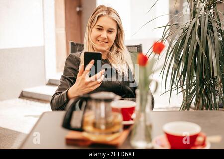 Une femme d'affaires en pause-café communique sur un téléphone intelligent ou prenez selfie Banque D'Images