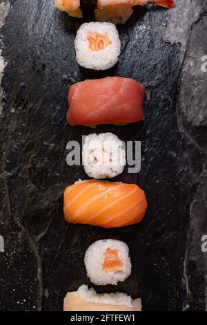 Gros plan de différents types de sushis sur une assiette en pierre noire. Banque D'Images