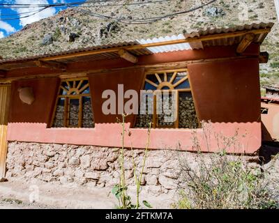 Urubamba, Pérou - 20 mai 2016: Matériaux locaux faits maison, avec des murs en adobe remplis de maïs récolte visible à travers les fenêtres. Amérique du Sud. Banque D'Images