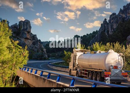 Camion-citerne avec des marchandises dangereuses circulant sur un viaduc entre les montagnes rocheuses. Banque D'Images