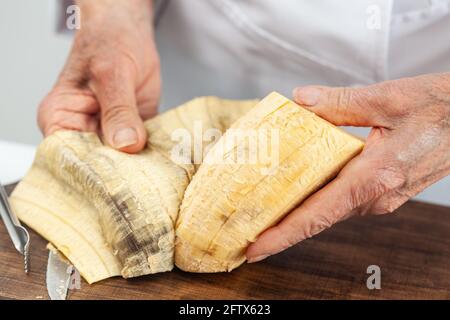 Gros plan d'une femme âgée mains tout en peeling un plantain mûr Banque D'Images
