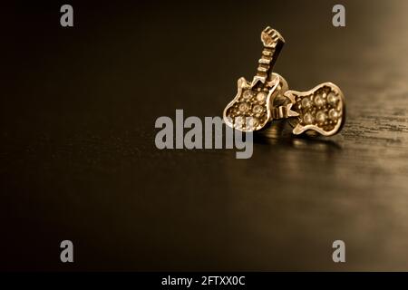 Un bijou en forme de guitare avec quelques diamants sur un noir table en bois Banque D'Images