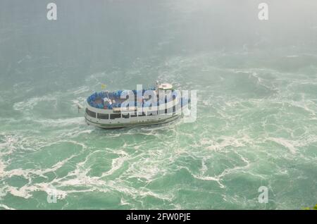 Niagara Falls, Canada - juillet 17 2013 : bateau touristique dans la brume des chutes du Niagara rempli de touristes en chapeaux de pluie bleus Banque D'Images