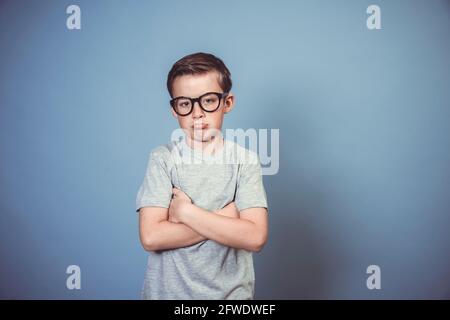 cool garçon d'école avec des lunettes noires épaisses posant sur bleu arrière-plan dans le studio Banque D'Images