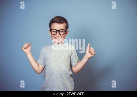 cool garçon d'école avec des lunettes noires épaisses posant sur bleu arrière-plan dans le studio Banque D'Images