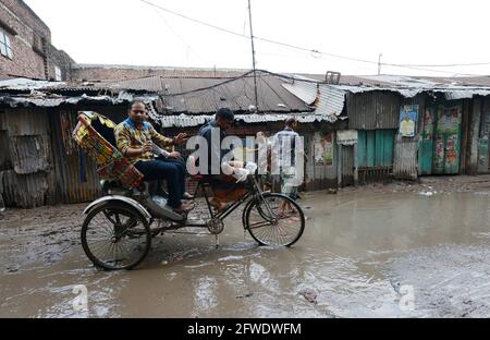 Vélo sur une route boueuse pendant la saison des pluies dans le vieux Dhaka, au Bangladesh. Banque D'Images