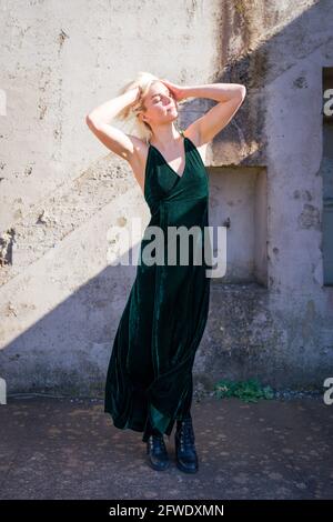 Mode dans des endroits inhabituels, femme en robe pleine longueur debout dans les ruines de la batterie d'arme à feu Banque D'Images