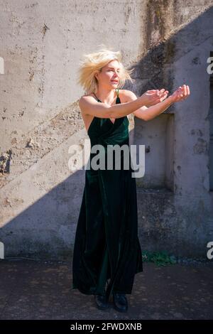 Mode dans des endroits inhabituels, femme en robe pleine longueur debout dans les ruines de la batterie d'arme à feu Banque D'Images