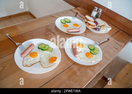 Œufs frits de deux œufs avec concombres et saucisses pour le petit déjeuner. Œufs frits, côté ensoleillé sur une assiette. Concept d'alimentation saine. Banque D'Images