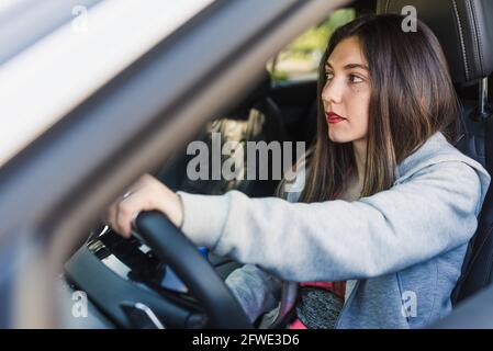 femme caucasienne attrayante conduisant une voiture vue de la fenêtre. Elle porte des vêtements de sport Banque D'Images