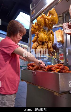 Un commerçant prépare le char siu ou le rôti de porc pour son service de boîte à lunch à son étal du marché de Tai Yuen. Banque D'Images