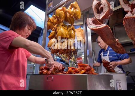 Un commerçant prépare le char siu ou le rôti de porc pour son service de boîte à lunch à son étal du marché de Tai Yuen. Banque D'Images