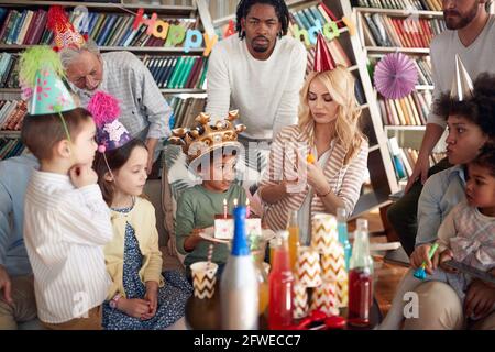 Famille et amis qui apprécient la célébration d'un anniversaire pour enfants dans une atmosphère festive à la maison. Famille, célébration, ensemble Banque D'Images