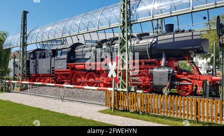 Vallée de Tauber, Allemagne - 11 août 2019 : exposition d'une ancienne locomotive à vapeur des chemins de fer allemands avec barrière de chemin de fer sous un ciel bleu. Banque D'Images