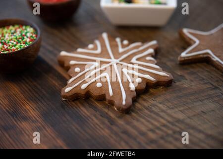 Flocons de neige au pain d'épice glacé avec étoile et arrosés sur une table en bois Banque D'Images