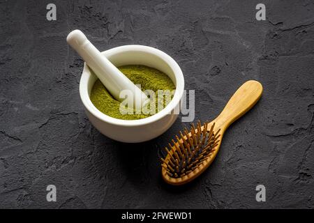 Poudre de teinture pour cheveux de henné et peigne en bois. Henné dans le mortier de wtite Banque D'Images