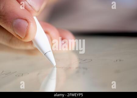 Main d'un jeune chercheur en mathématiques ou d'un étudiant qui écrit formules mathématiques et symboles scientifiques sur une tablette numérique utilisant un stylet gros plan Banque D'Images