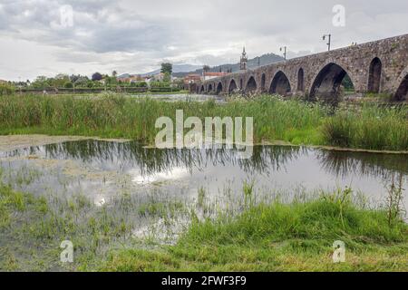 Vieux pont en granit et église de la ville médiévale de Ponte de Lima en un jour pluvieux. Chemin du nord portugais vers Saint-Jacques-de-Compostelle. Banque D'Images