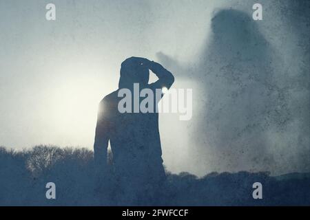 Une figure à capuche solitaire, de retour à la caméra, regardant une figure fantôme géante d'une femelle flottant dans le ciel. Avec un résumé, grunge, modifier. Banque D'Images