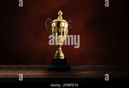 prix du 1er champion, le meilleur prix et le meilleur concept, coupe de championnat ou trophée du gagnant sur table en bois sur fond de mur noir et brun foncé Banque D'Images