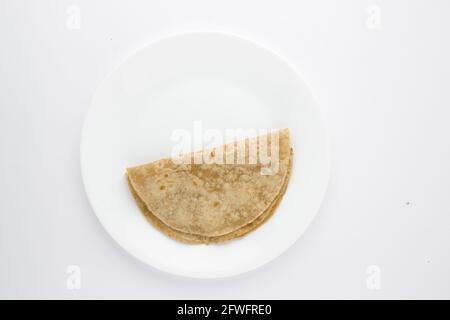 Smiley visage nourriture article chappati, nourriture saine faite de farine de blé disposés sur plaque blanche en céramique avec fond blanc de couleur. Banque D'Images