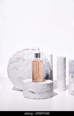 Podium pour la publicité et la présentation de l'emballage des produits cosmétiques de sérum. Socle de beauté naturelle avec texture marbre en plein soleil sur fond blanc Banque D'Images