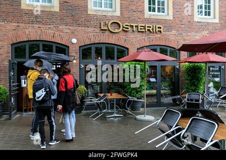 Münster, NRW, Allemagne. 22 mai 2021. Une file d'attente devant le populaire restaurant l'Osteria. La foule se rassemble dans le centre-ville historique de Münster, malgré les fortes pluies, car elle devient la première ville de Rhénanie-du-Nord-Westphalie à avoir le droit d'ouvrir des boissons et des repas à l'intérieur (avec test négatif ou vaccination), et des achats sans test ou rendez-vous (mais les chiffres sont limités). Münster a actuellement l'un des taux d'incidence de covid les plus bas en NRW à 17/100k et est devenu une « région de modèle » pour essayer la réouverture lente des lieux d'accueil. Credit: Imagetraceur/Alamy Live News Banque D'Images