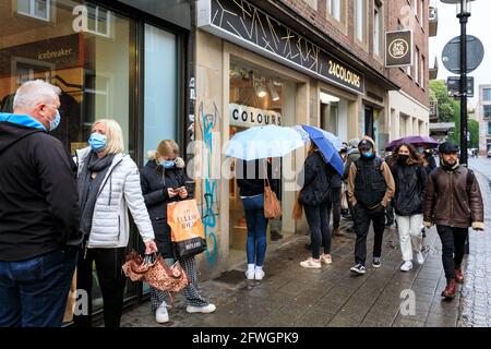 Münster, NRW, Allemagne. 22 mai 2021. Files d'attente à l'extérieur d'un magasin appelé « 24 couleurs ». La foule se rassemble dans le centre-ville historique de Münster, malgré les fortes pluies, car elle devient la première ville de Rhénanie-du-Nord-Westphalie à avoir le droit d'ouvrir des boissons et des repas à l'intérieur (avec test négatif ou vaccination), et des achats sans test ou rendez-vous (mais les chiffres sont limités). Münster a actuellement l'un des taux d'incidence de covid les plus bas en NRW à 17/100k et est devenu une « région de modèle » pour essayer la réouverture lente des lieux d'accueil. Credit: Imagetraceur/Alamy Live News Banque D'Images