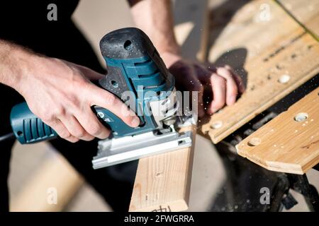 03 avril 2021, Basse-Saxe, Großenmeer: Hannes Wehrmann scie le bois devant sa Mercedes-Benz Sprinter, qu'il transforme en campervan avec sa petite amie Greta Thomas. Photo: Hauke-Christian Dittrich/dpa Banque D'Images