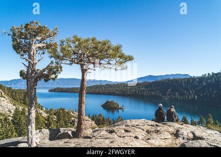 Deux personnes s'assoient sur un rocher surplombant Emerald Bay, Lake Tahoe, Californie Banque D'Images