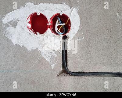 Les fils électriques avec les câbles à la maison. Nouvelles prises électriques. Prise murale en béton Banque D'Images