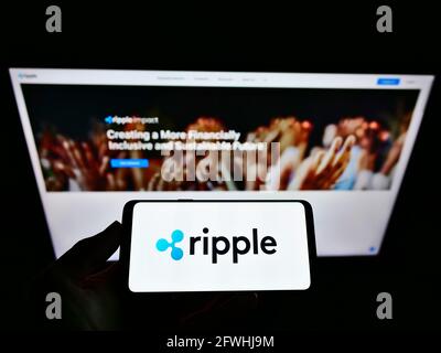 Personne tenant un smartphone avec le logo de la société américaine de technologie Ripple Labs Inc. À l'écran devant le site Web. Mise au point sur l'affichage du téléphone. Banque D'Images